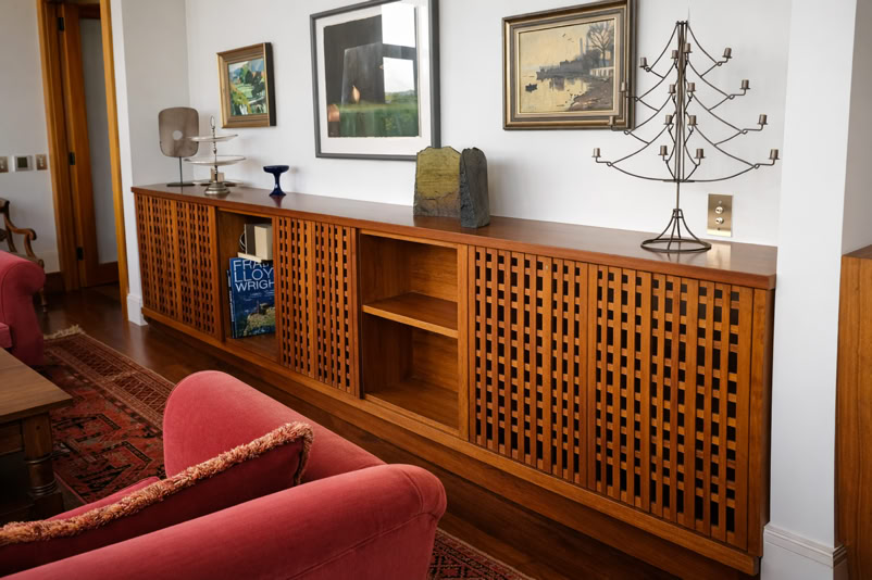 A wooden sideboard with lattice doors, decorative items on top, and framed artwork on the wall above.