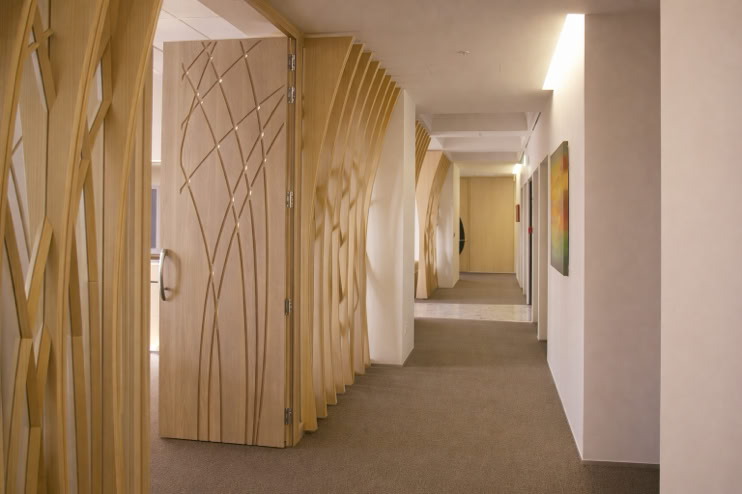 A hallway with decorative wooden panels featuring abstract designs, beige walls, and a carpeted floor.