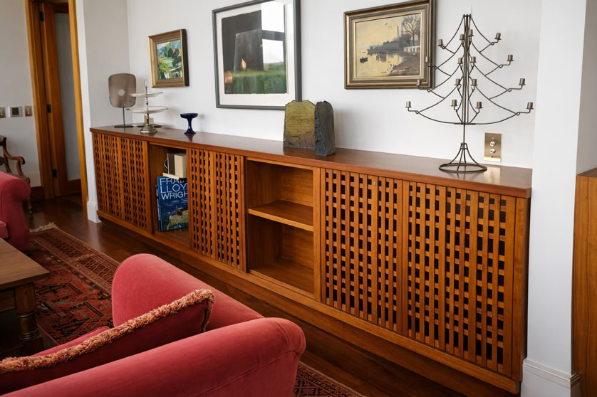 Wooden sideboard with lattice doors, decorative items on top, and framed artwork on the wall above.