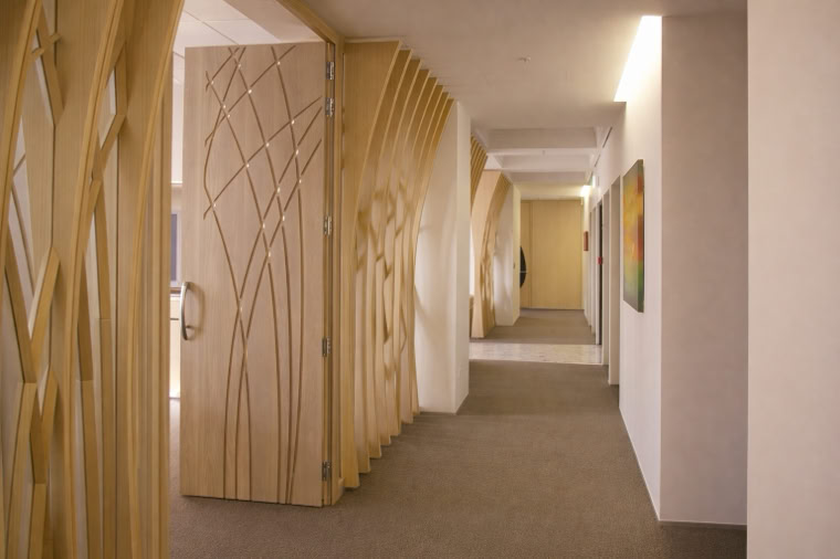 A hallway with decorative wooden panels featuring abstract tree designs, beige walls, and a carpeted floor.