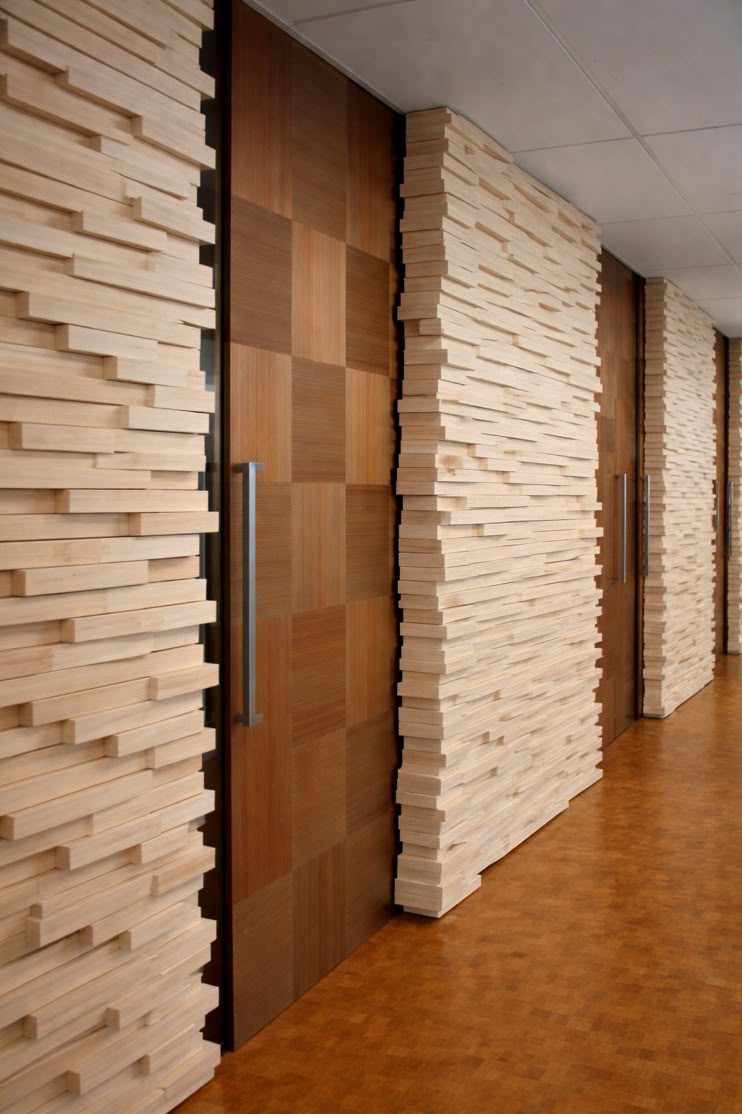 Wood-paneled hallway with textured walls and a wooden door featuring a vertical handle.