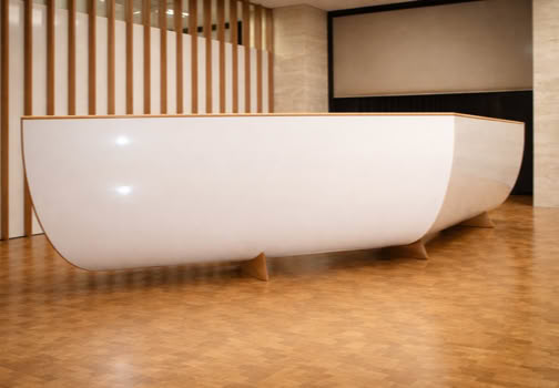 A large, white, curved reception desk in a room with wooden flooring and vertical wooden slats on the wall.