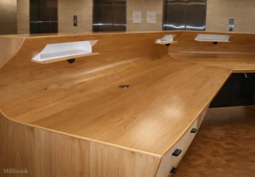 Wooden courtroom bench with built-in microphones and white document holders.